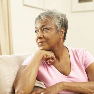 Senior Woman Looking Thoughtful In Chair At Home